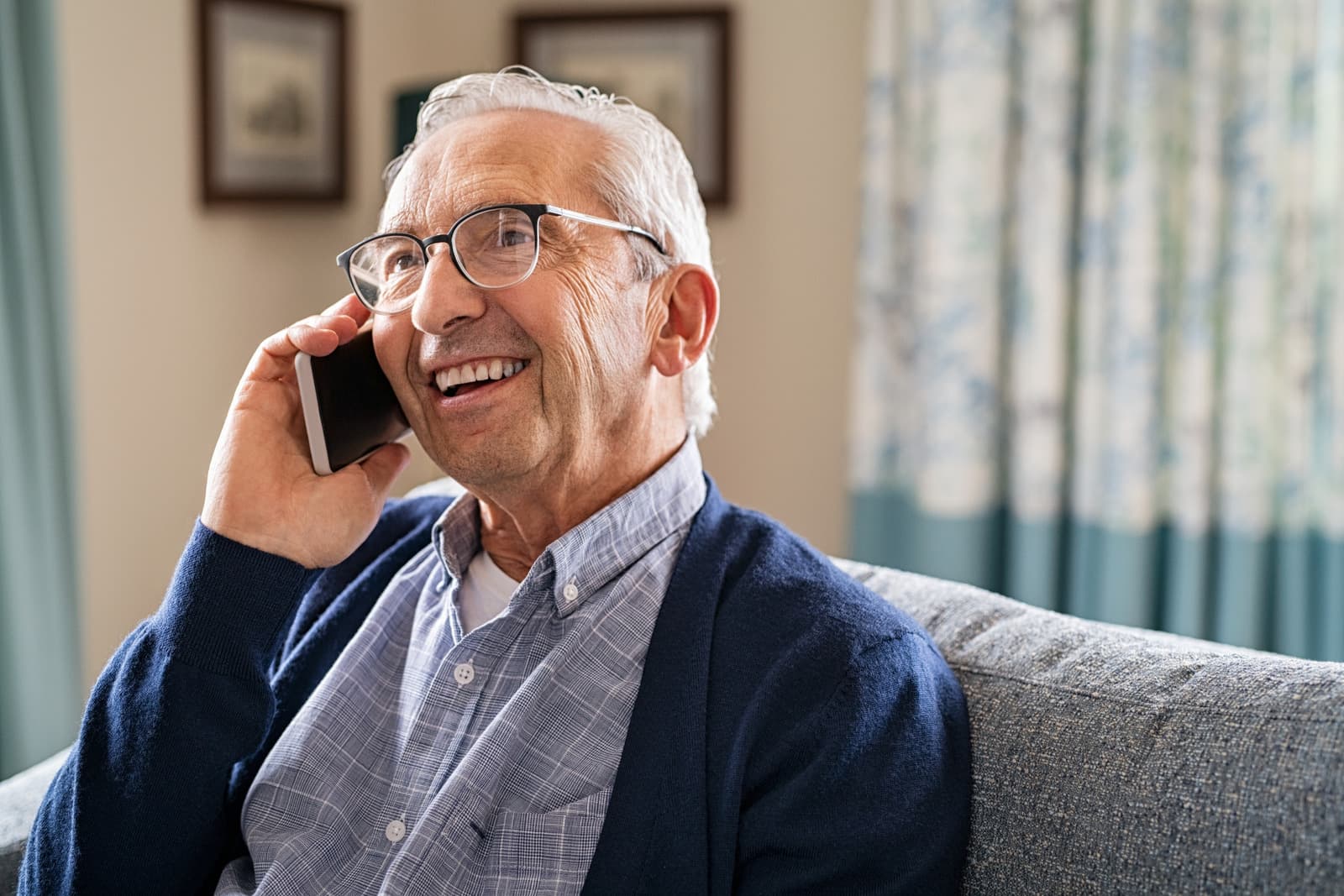 An older man smiling while talking on the phone